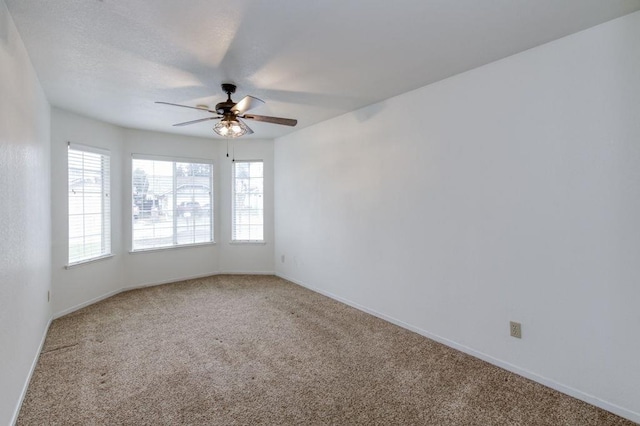 carpeted spare room with a ceiling fan, baseboards, and a textured ceiling