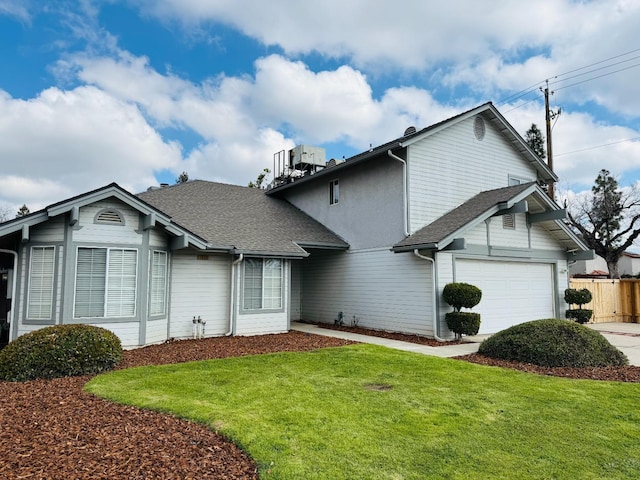 view of front of home featuring a garage, roof with shingles, a front yard, and fence