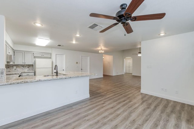 kitchen featuring visible vents, arched walkways, freestanding refrigerator, a peninsula, and a sink