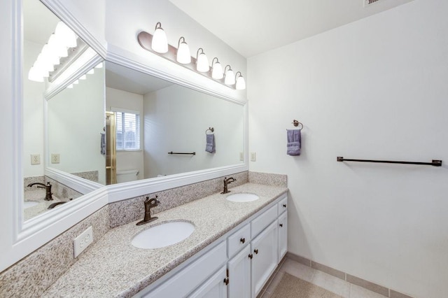 bathroom with tile patterned floors, a sink, toilet, and double vanity