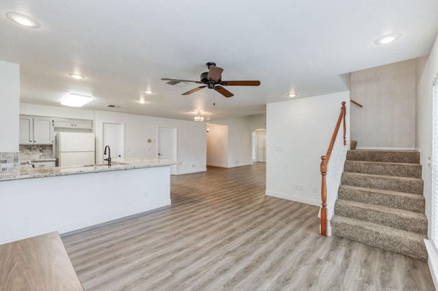 kitchen featuring ceiling fan, arched walkways, light wood-type flooring, freestanding refrigerator, and tasteful backsplash