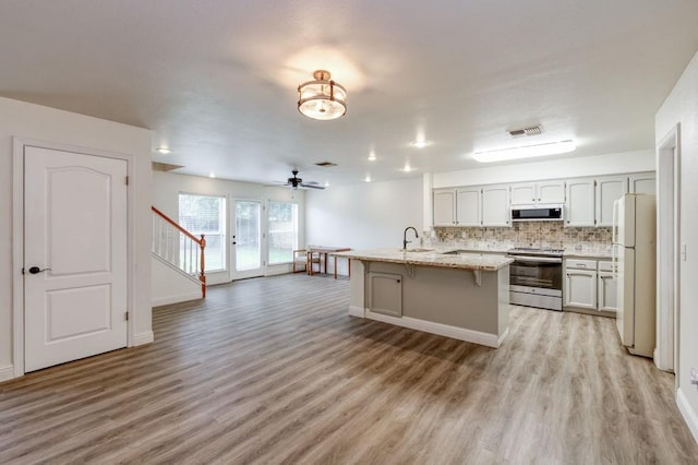 kitchen with white appliances, visible vents, a breakfast bar, open floor plan, and a sink