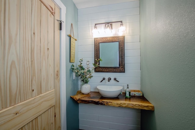 bathroom featuring wooden walls, a textured wall, and vanity