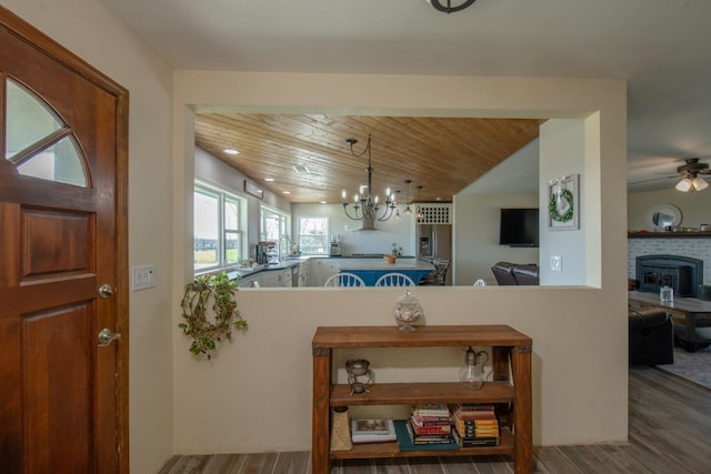 kitchen featuring decorative light fixtures, a fireplace, wood finished floors, wooden ceiling, and ceiling fan with notable chandelier