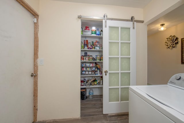 clothes washing area featuring washer / dryer, laundry area, a barn door, and wood finished floors