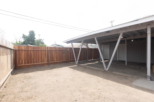 view of parking / parking lot featuring a carport and a fenced backyard