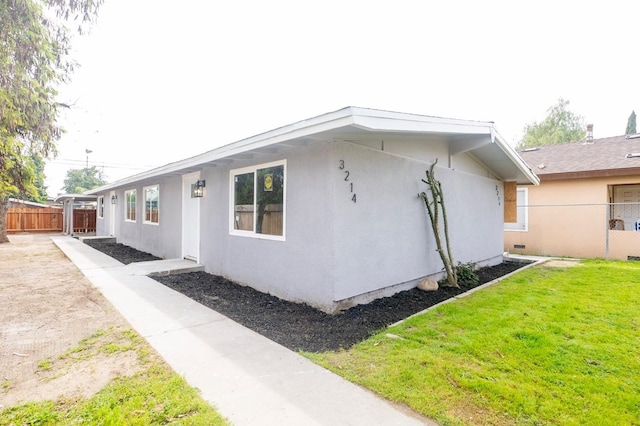 view of home's exterior featuring fence, a lawn, and stucco siding