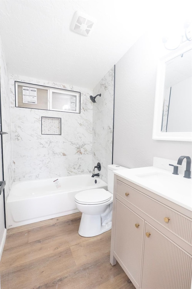 bathroom featuring visible vents, toilet, wood finished floors, tub / shower combination, and vanity