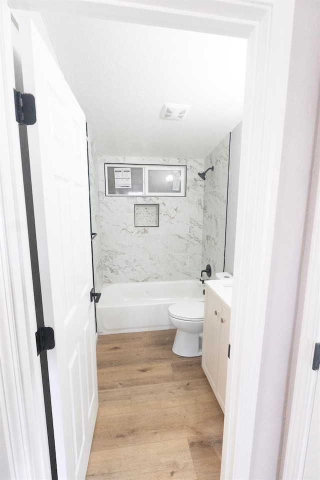 bathroom featuring toilet, shower / bath combination, wood finished floors, visible vents, and vanity