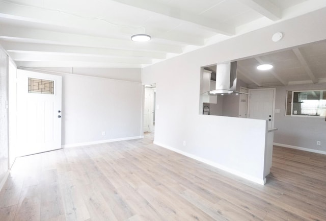 unfurnished living room with lofted ceiling with beams, light wood finished floors, and baseboards