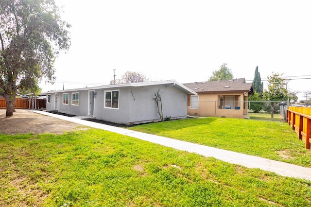 rear view of house featuring a fenced backyard, a yard, and stucco siding