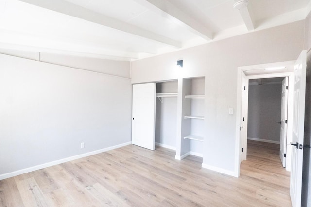 unfurnished bedroom featuring a closet, beamed ceiling, wood finished floors, and baseboards