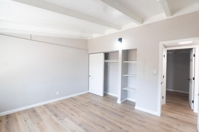 unfurnished bedroom featuring light wood finished floors, a closet, baseboards, and beam ceiling