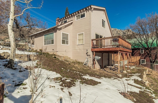 snow covered property featuring stairway and a deck