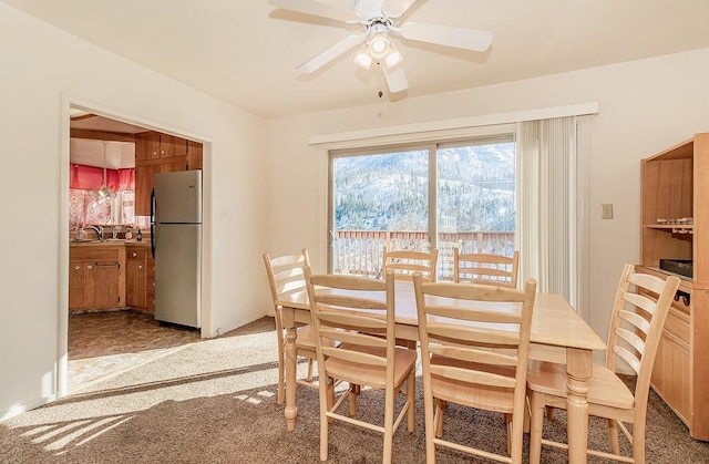 dining area with ceiling fan and light carpet