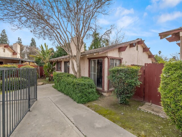 2103 N Price Ave Unit 106, Fresno, CA 93703 - view of front facade featuring stucco siding, fence, and a gate
