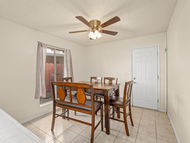 dining room with ceiling fan, baseboards, a textured ceiling, and light tile patterned flooring