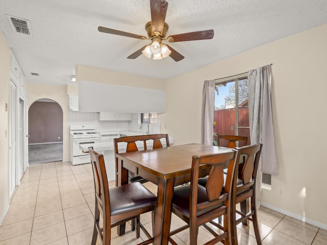 2103 N Price Ave Unit 106, Fresno, CA 93703 - dining area featuring light tile patterned floors, arched walkways, baseboards, a ceiling fan, and a textured ceiling