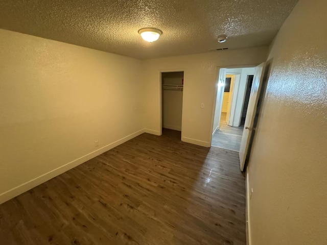 2004 E White Ave, Fresno, CA 93701 - unfurnished bedroom featuring dark wood finished floors, a textured ceiling, baseboards, and a closet