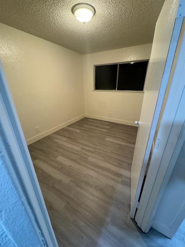 2004 E White Ave, Fresno, CA 93701 - unfurnished room featuring dark wood-type flooring, a textured ceiling, and baseboards