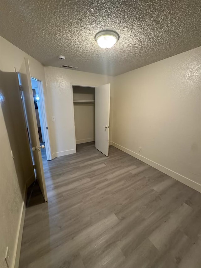 2004 E White Ave, Fresno, CA 93701 - unfurnished bedroom featuring a textured ceiling, wood finished floors, a closet, and baseboards
