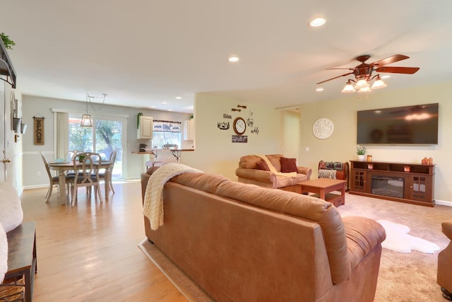 living room with recessed lighting, light wood-style flooring, a ceiling fan, a glass covered fireplace, and baseboards