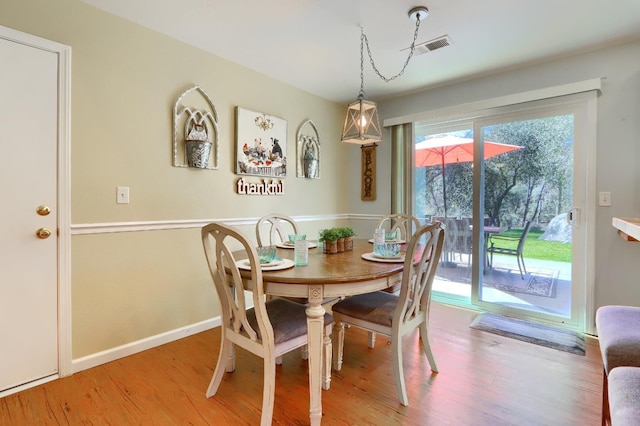 dining area with wood finished floors, visible vents, and baseboards