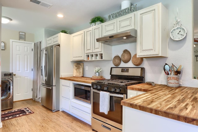 kitchen featuring stainless steel appliances, butcher block countertops, washer / dryer, and under cabinet range hood