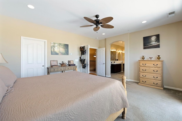 bedroom with arched walkways, recessed lighting, light colored carpet, visible vents, and baseboards