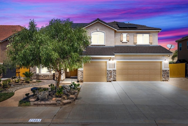 view of front of home with stone siding, stucco siding, a tile roof, and roof mounted solar panels