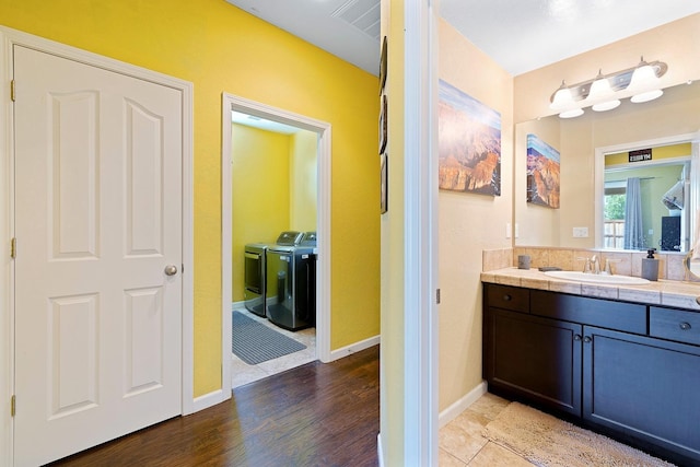 bathroom with wood finished floors, visible vents, baseboards, vanity, and washer and dryer