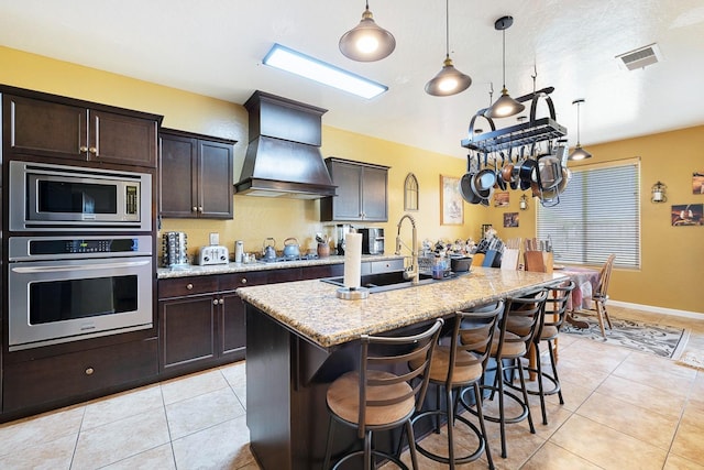 kitchen with light tile patterned floors, a sink, visible vents, appliances with stainless steel finishes, and custom range hood