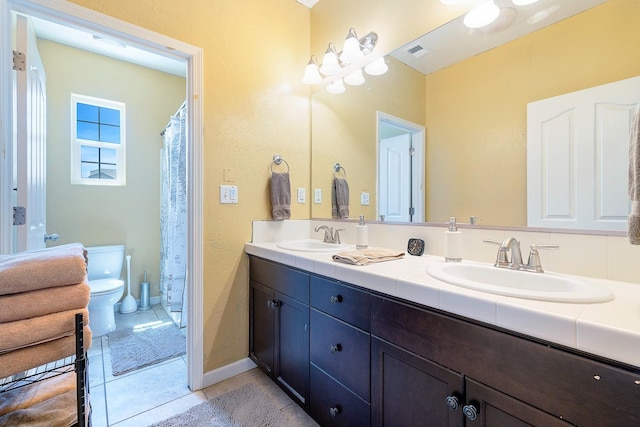 bathroom with double vanity, visible vents, a sink, and tile patterned floors