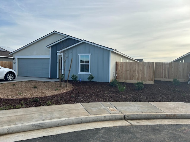 view of front of house with an attached garage, driveway, fence, and board and batten siding