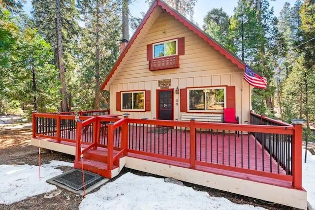 rear view of house featuring board and batten siding and a wooden deck