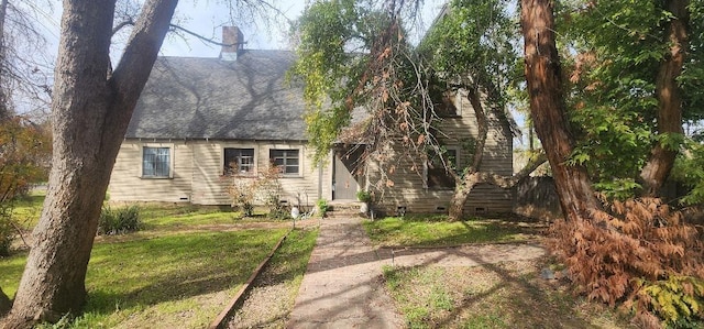 new england style home featuring crawl space, a chimney, and a front yard