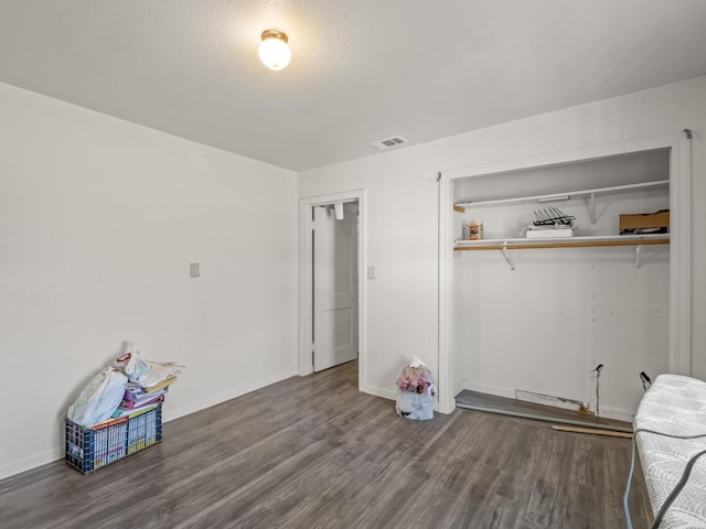 unfurnished bedroom with baseboards, visible vents, a closet, and wood finished floors