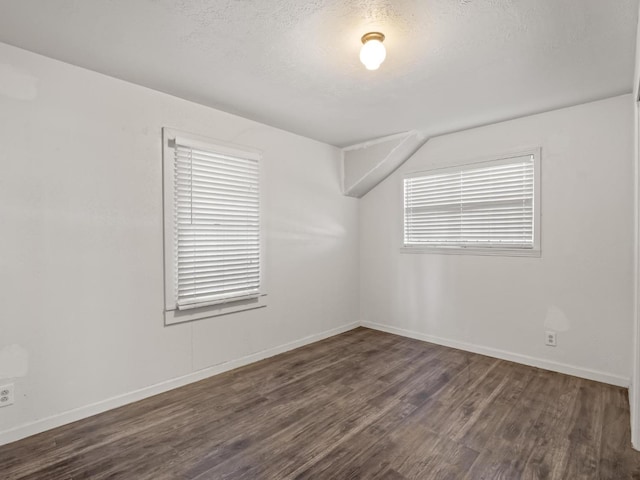 unfurnished room featuring a textured ceiling, dark wood-type flooring, and baseboards