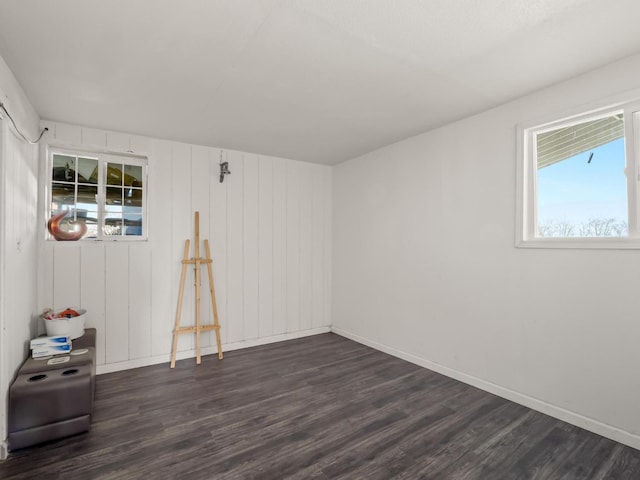 empty room featuring baseboards, dark wood-type flooring, and a healthy amount of sunlight