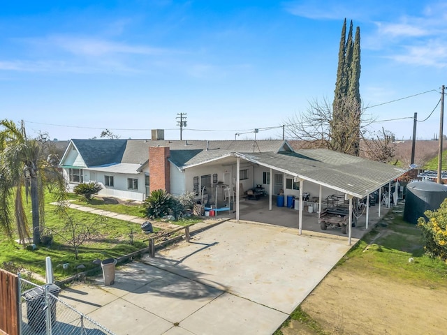 rear view of house with driveway and fence