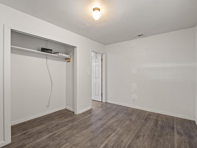 unfurnished bedroom featuring a closet, visible vents, baseboards, and wood finished floors