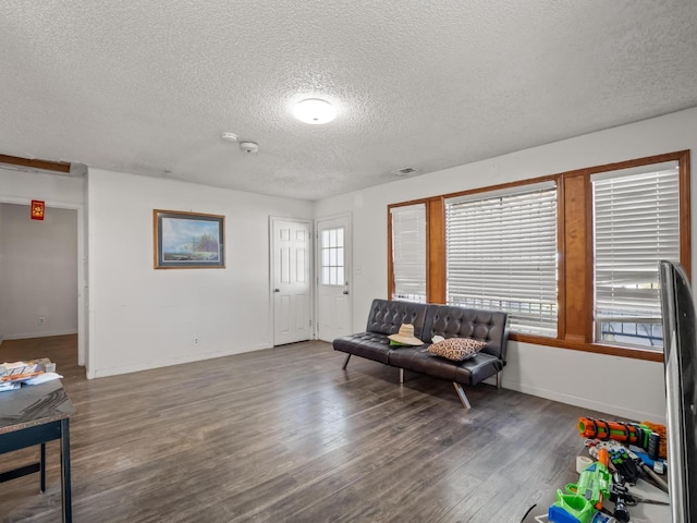 interior space with visible vents, a textured ceiling, baseboards, and wood finished floors