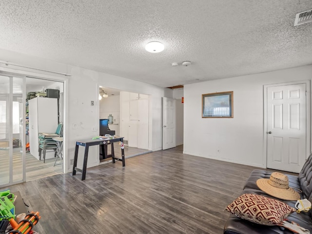 interior space with visible vents, a textured ceiling, baseboards, and wood finished floors