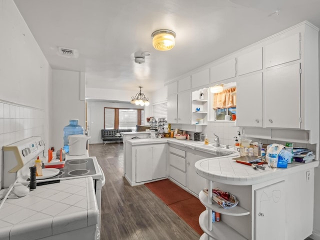 kitchen with a sink, tile countertops, a peninsula, and open shelves