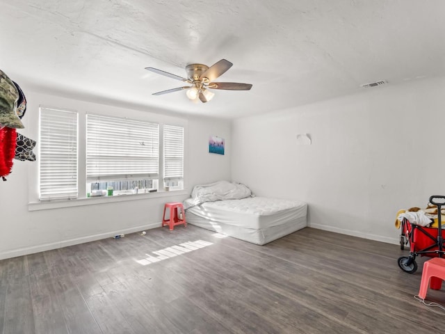 bedroom featuring a ceiling fan, visible vents, baseboards, and wood finished floors