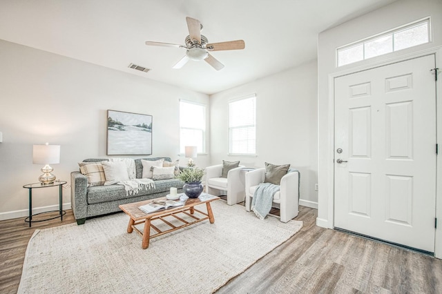 living area featuring visible vents, ceiling fan, baseboards, and wood finished floors