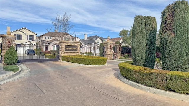 exterior space featuring a residential view, a gate, a gated entry, and curbs