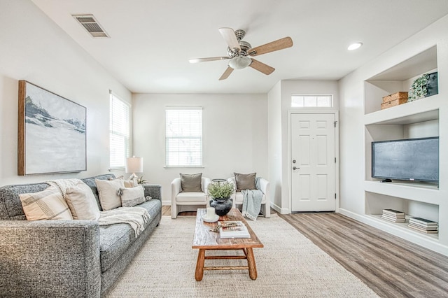 living area with light wood-style flooring, visible vents, ceiling fan, and baseboards