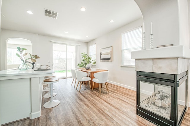 dining space featuring arched walkways, recessed lighting, visible vents, baseboards, and light wood-style floors