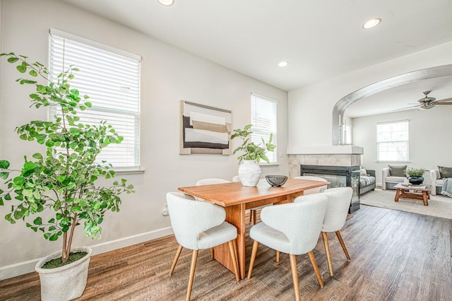 dining space featuring ceiling fan, a tile fireplace, recessed lighting, wood finished floors, and baseboards